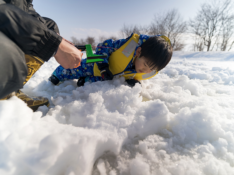 ワカサギが釣れるか覗き込む子供